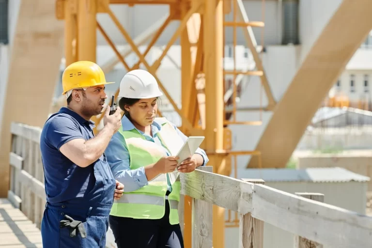 two industrial workers on site - one using tablet, the other communicating via radio